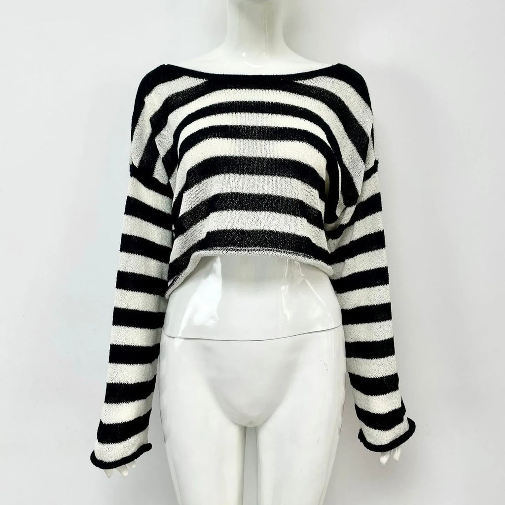 A woman wearing a cropped black and white striped long-sleeved sweater with a front and back exposed-navel design.
