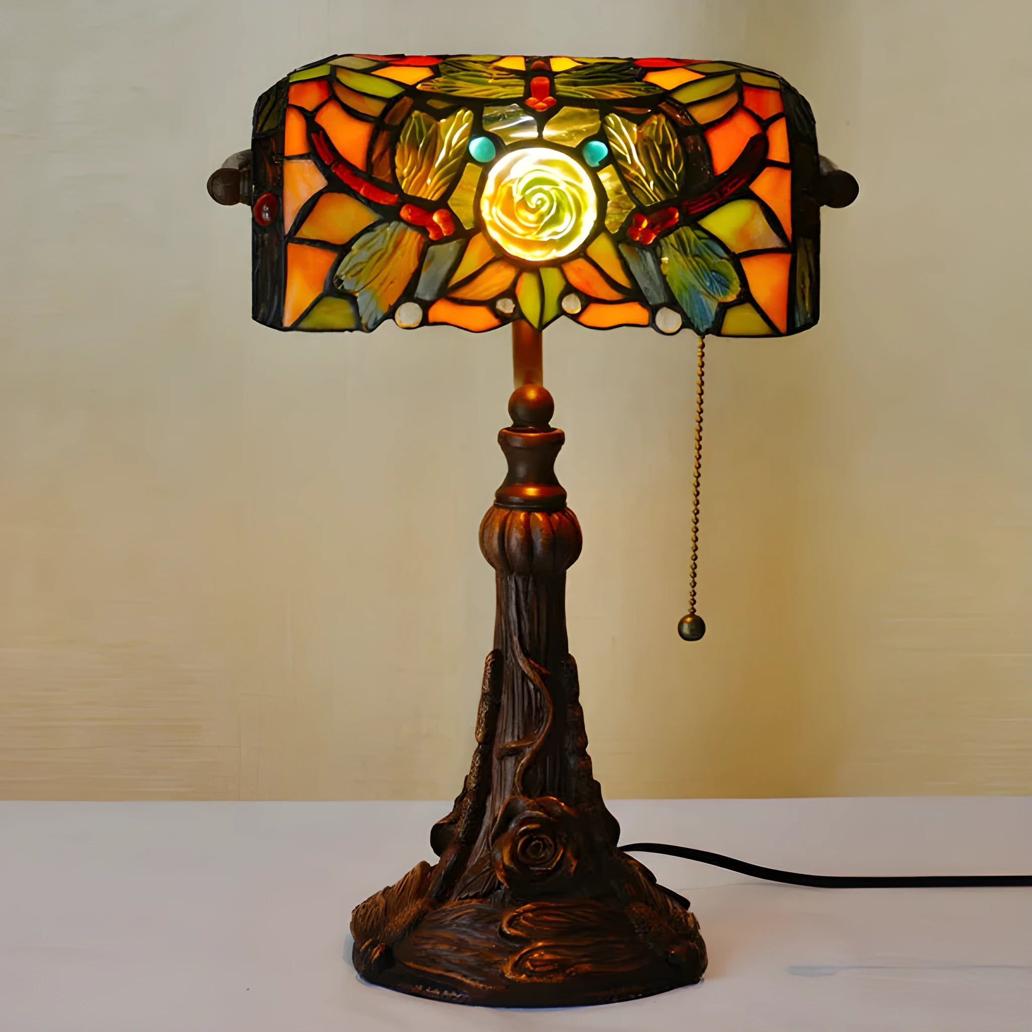 Tiffany-style desk lamp with a coloured stained glass shade on a resin base.