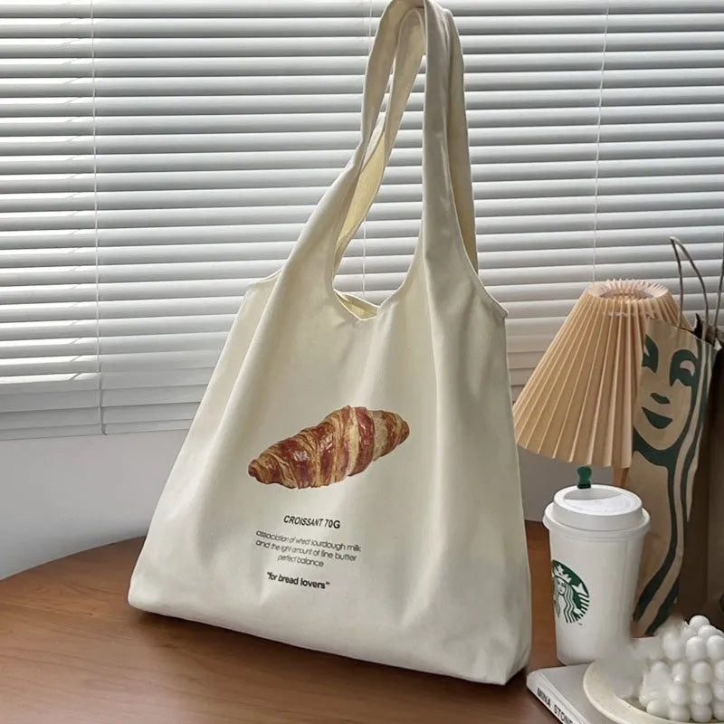 Beige canvas shoulder tote bag with a decorative bread and croissant print design.