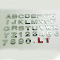 Close-up of a black zinc alloy 3D letter 'A' car bumper sticker on a silver vehicle panel.