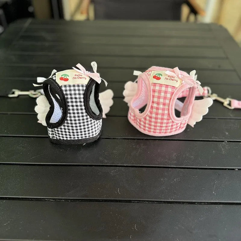 Pink and black cotton chest and back hand holding rope harness for a small dog on a white background.