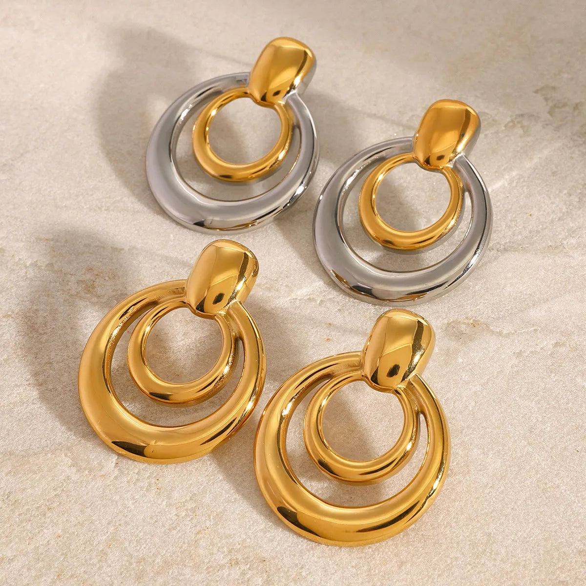 A pair of round, golden, hollow double layer stud earrings made from titanium steel with 18K gold electroplating.