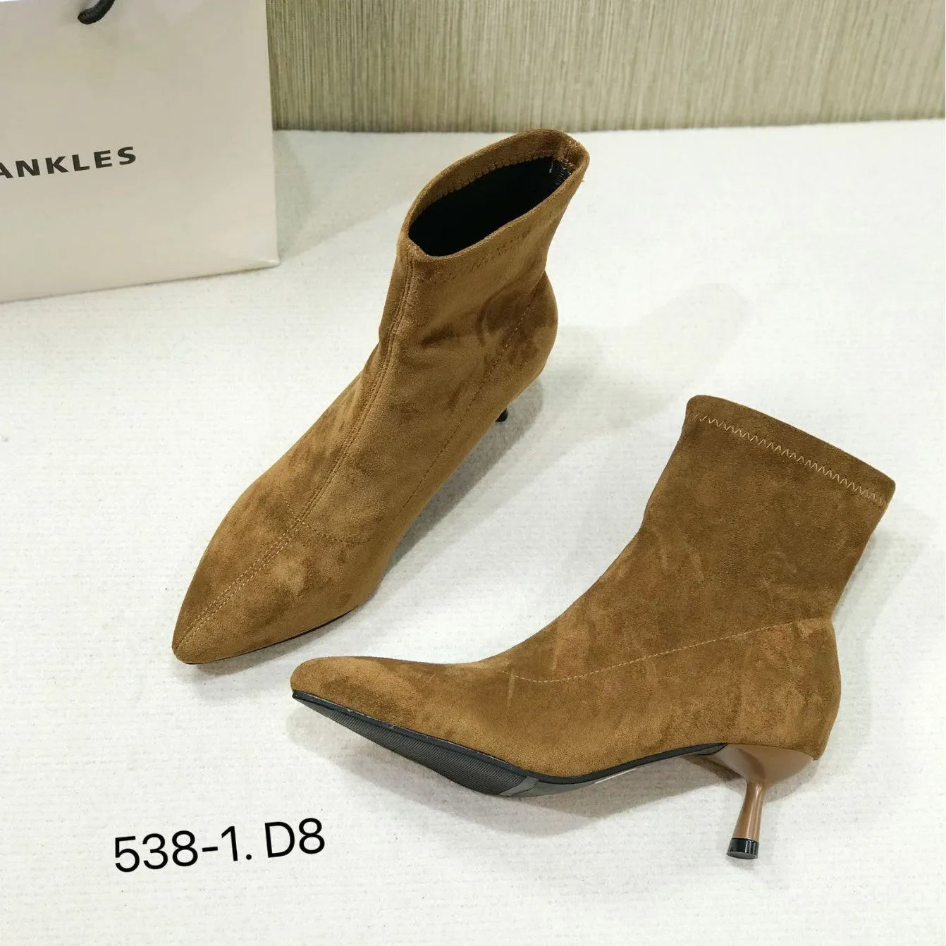 Black pointed toe women's ankle boot with a stiletto heel on a plain background.