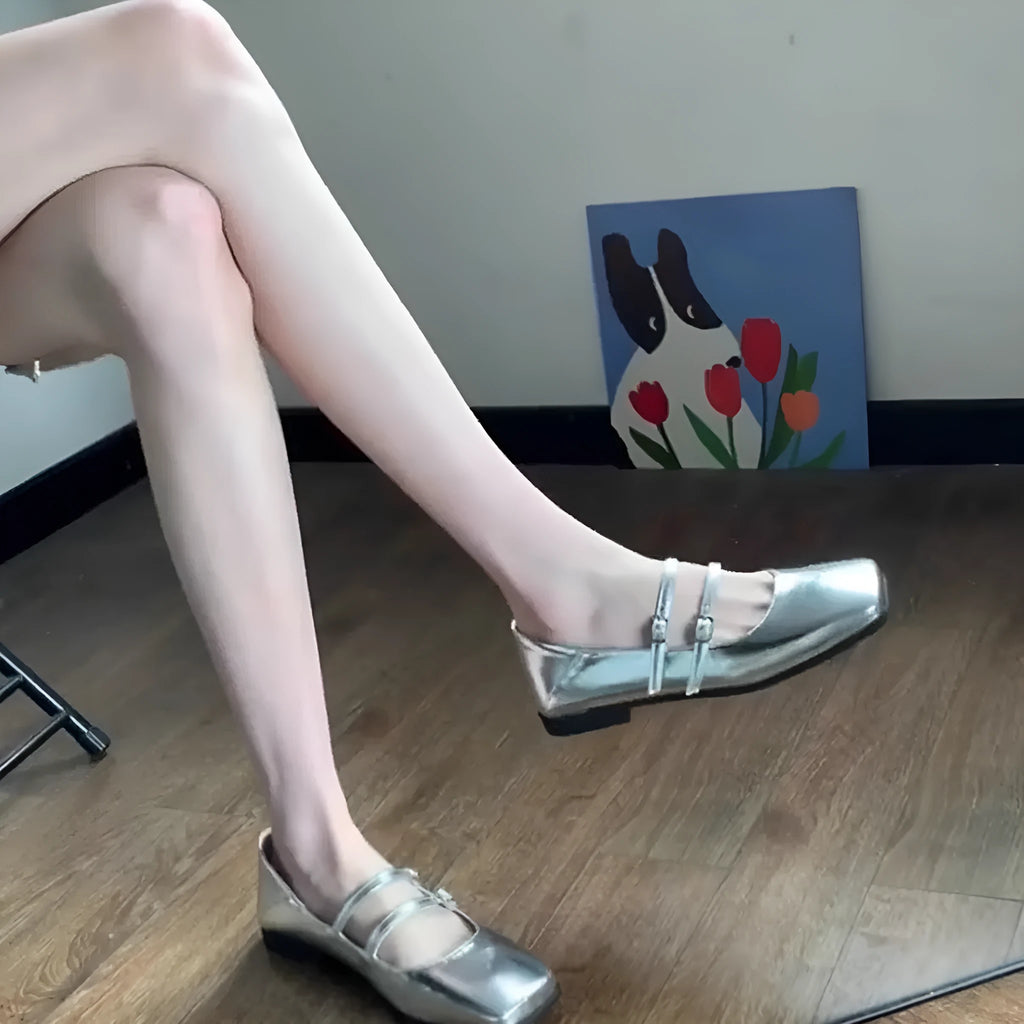Women's silver leather Mary Jane flats with a cross-buckle strap and flat heel.
