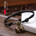 Close-up of an adjustable black nylon rope dog collar featuring a shiny brass bell.