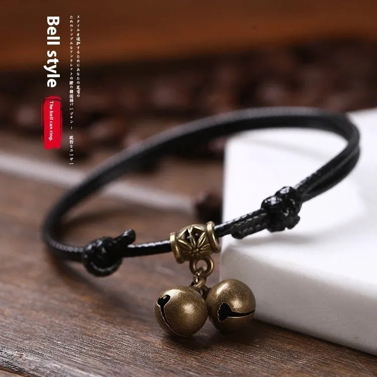 Close-up of an adjustable black nylon rope dog collar featuring a shiny brass bell.