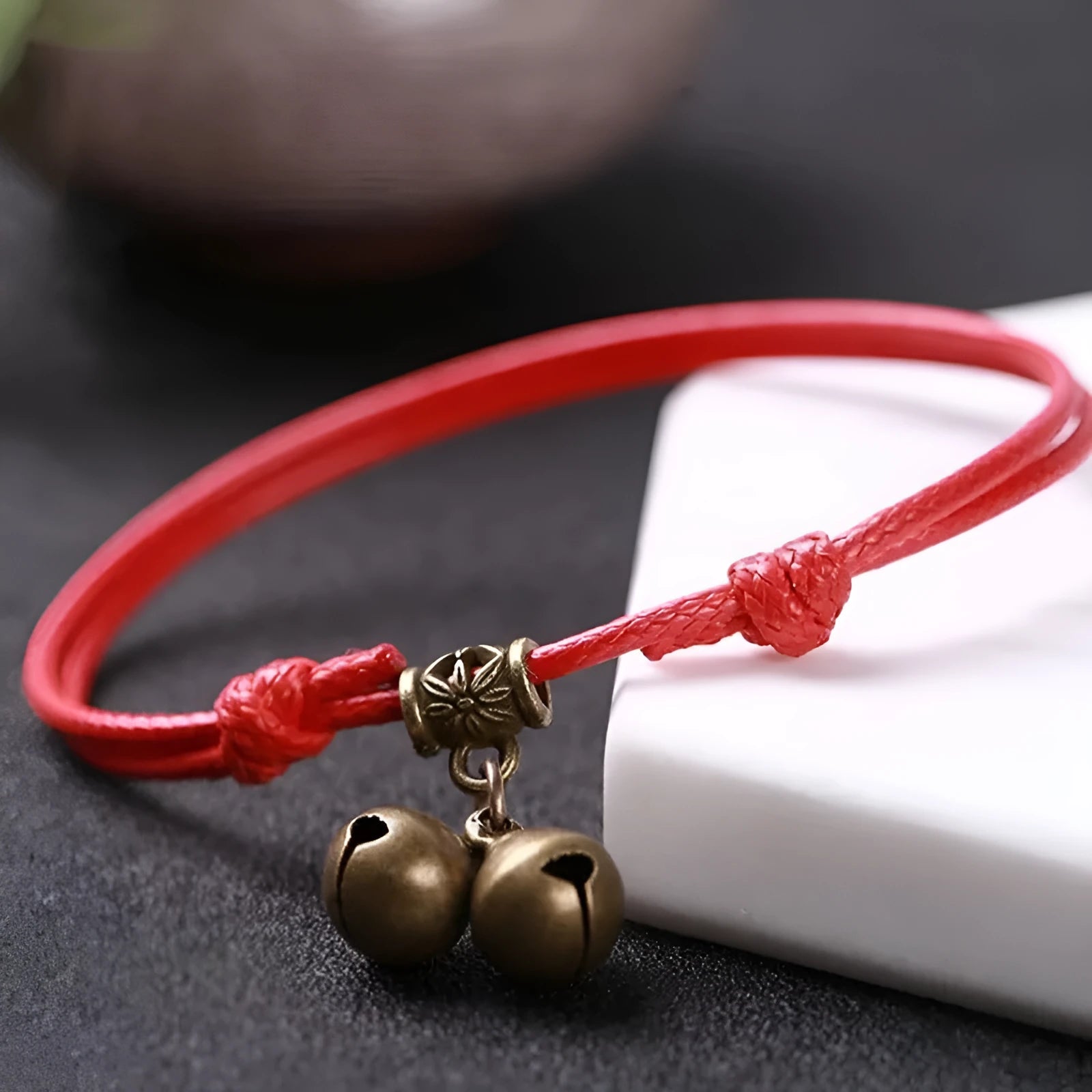 Close-up of an adjustable black nylon rope dog collar featuring a shiny brass bell.