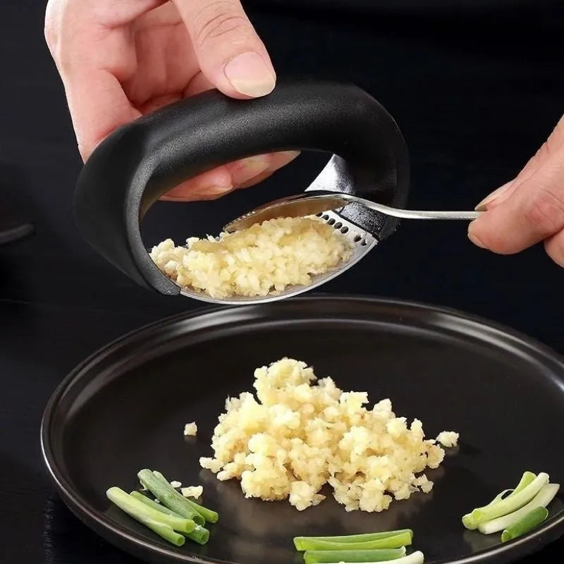 Stainless steel garlic press with coloured ergonomic handle on a kitchen counter.