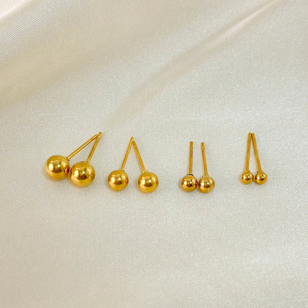 Close-up of a small spherical stainless steel stud earring with a polished electroplated finish on a grey background.