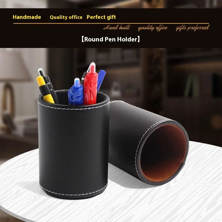 Round black leather pen container on a desk holding pens and pencils.