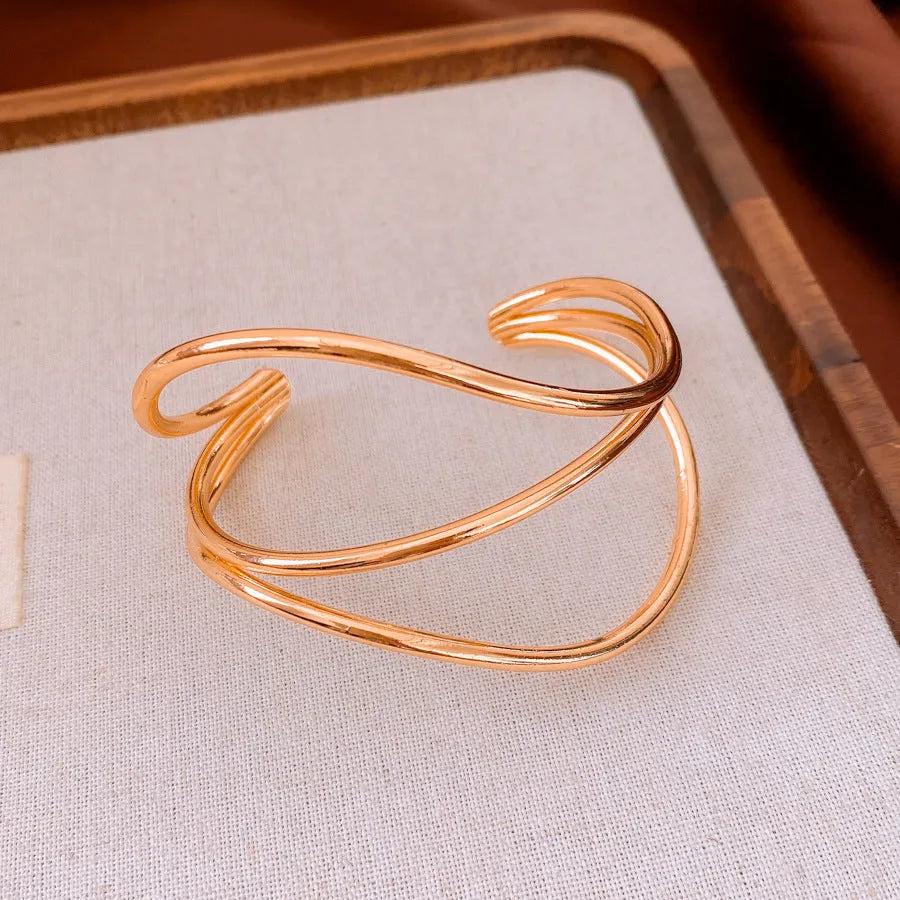 Open-ended metal bracelet with geometric irregular lines, round element, available in gold or silver