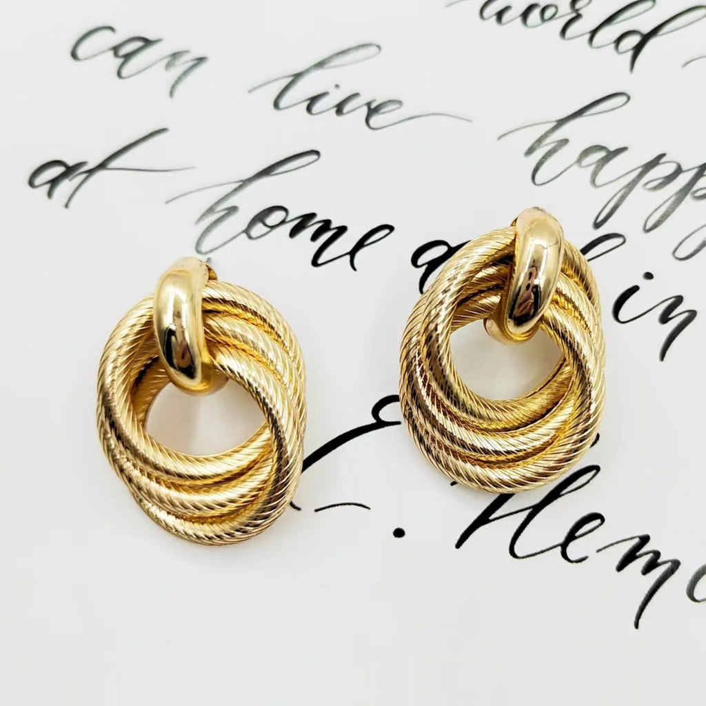 Gold metal geometric ring embossed twisted stud earrings on display