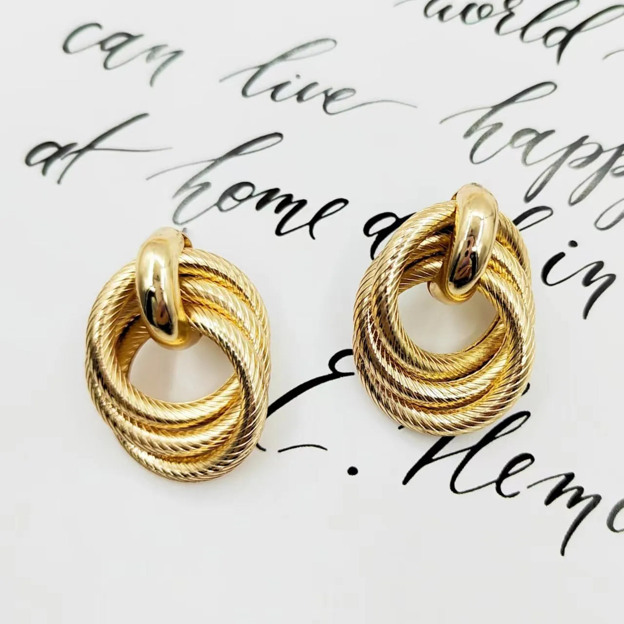 Gold metal geometric ring embossed twisted stud earrings on display