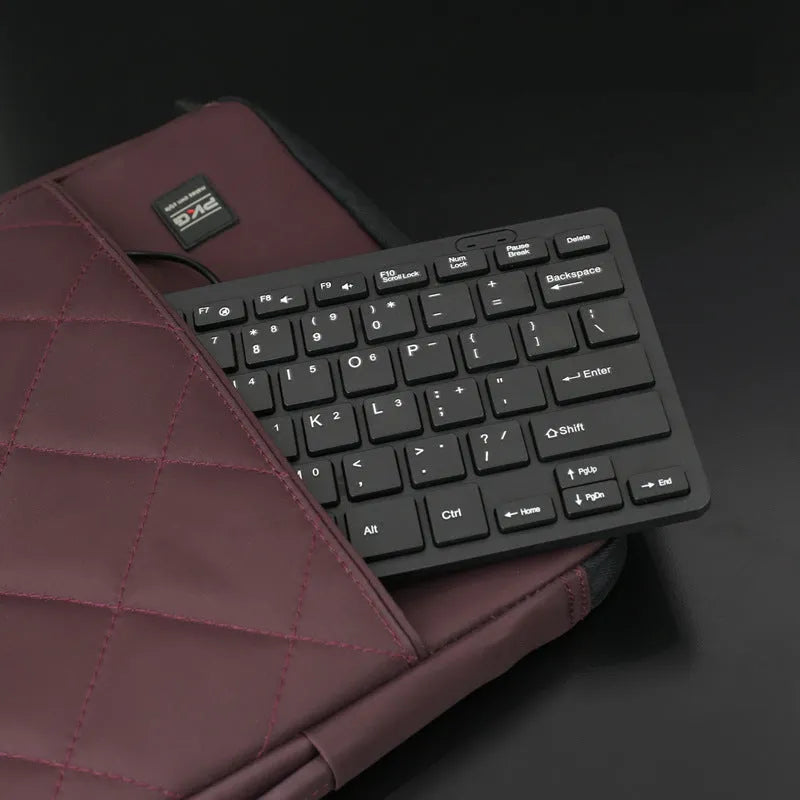 USB wired mini computer keyboard in black, white, pink, or blue colour on a desk.