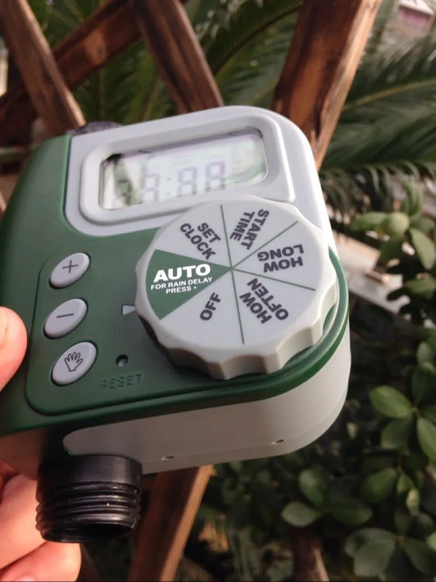 Green digital programmable hose timer with metal faucet connector and dual outlet ports for garden watering