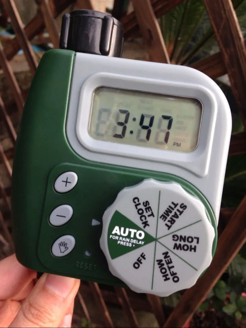 Green digital programmable hose timer with metal faucet connector and dual outlet ports for garden watering