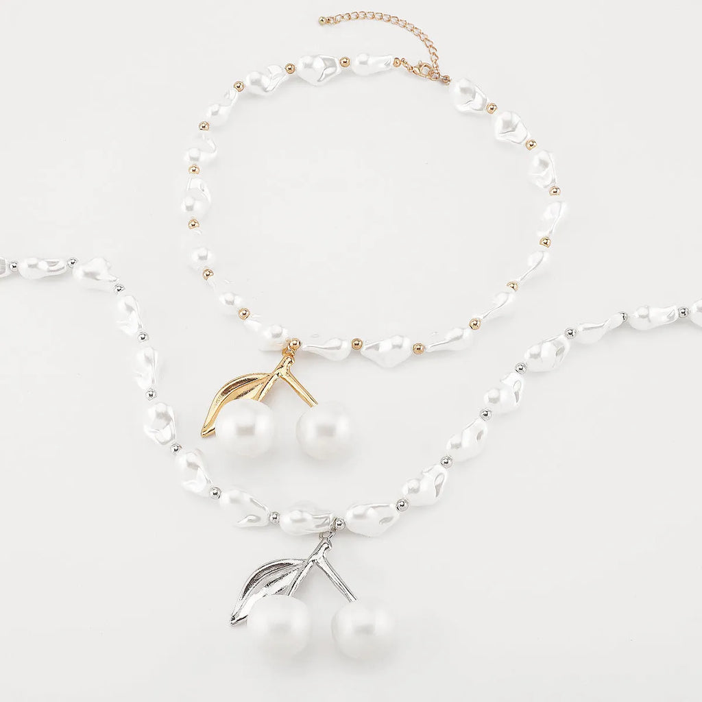 Gold-tone adjustable necklace with imitation pearls and cherry fruit pendants on a white background.
