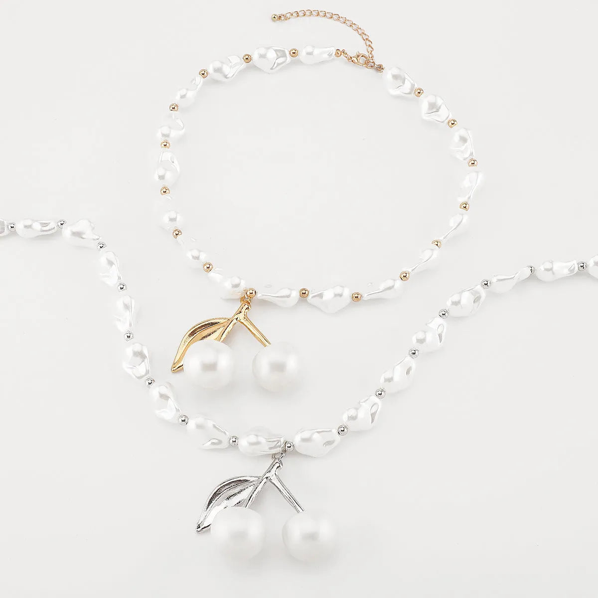 Gold-tone adjustable necklace with imitation pearls and cherry fruit pendants on a white background.