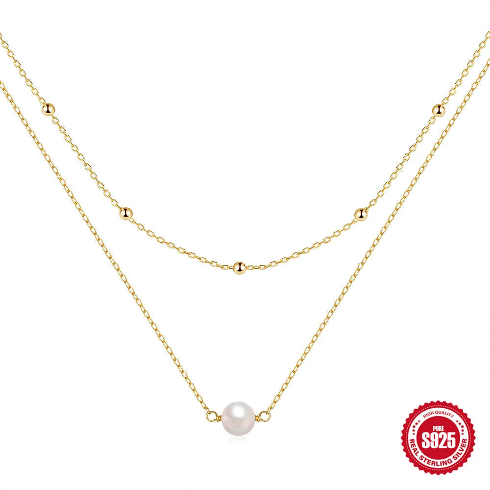 Close-up of a double-layer sterling silver necklace with twin pearl geometric pendants on a ball bead chain.