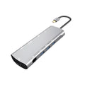 Grey aluminium USB-C docking station with HDMI, VGA, USB, and charging ports on a wooden desk.