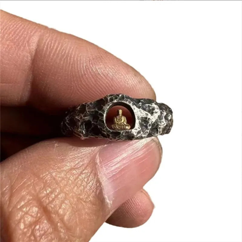 Close-up of a hand-forged copper ring with a Grotto Buddha design and rock texture.