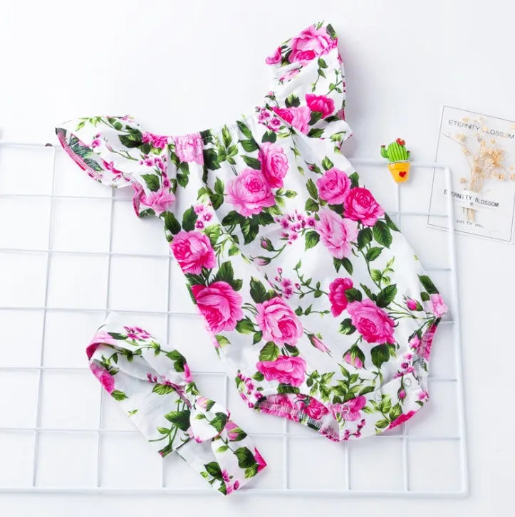 Baby girl in a black cotton romper with small flying sleeves print, showing sleeveless triangle climbing style.