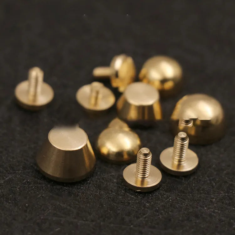 Brass decorative buckle with set of round and bucket-shaped brass foot nails on a surface.