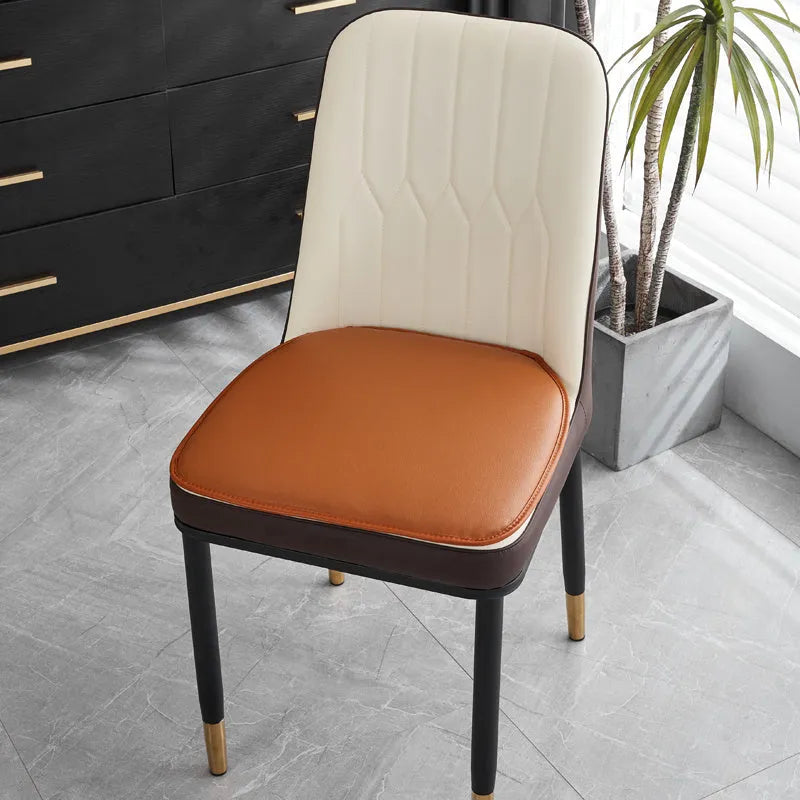 Solid colour leather horseshoe-shaped seat cushion with a non-slip base on a chair.