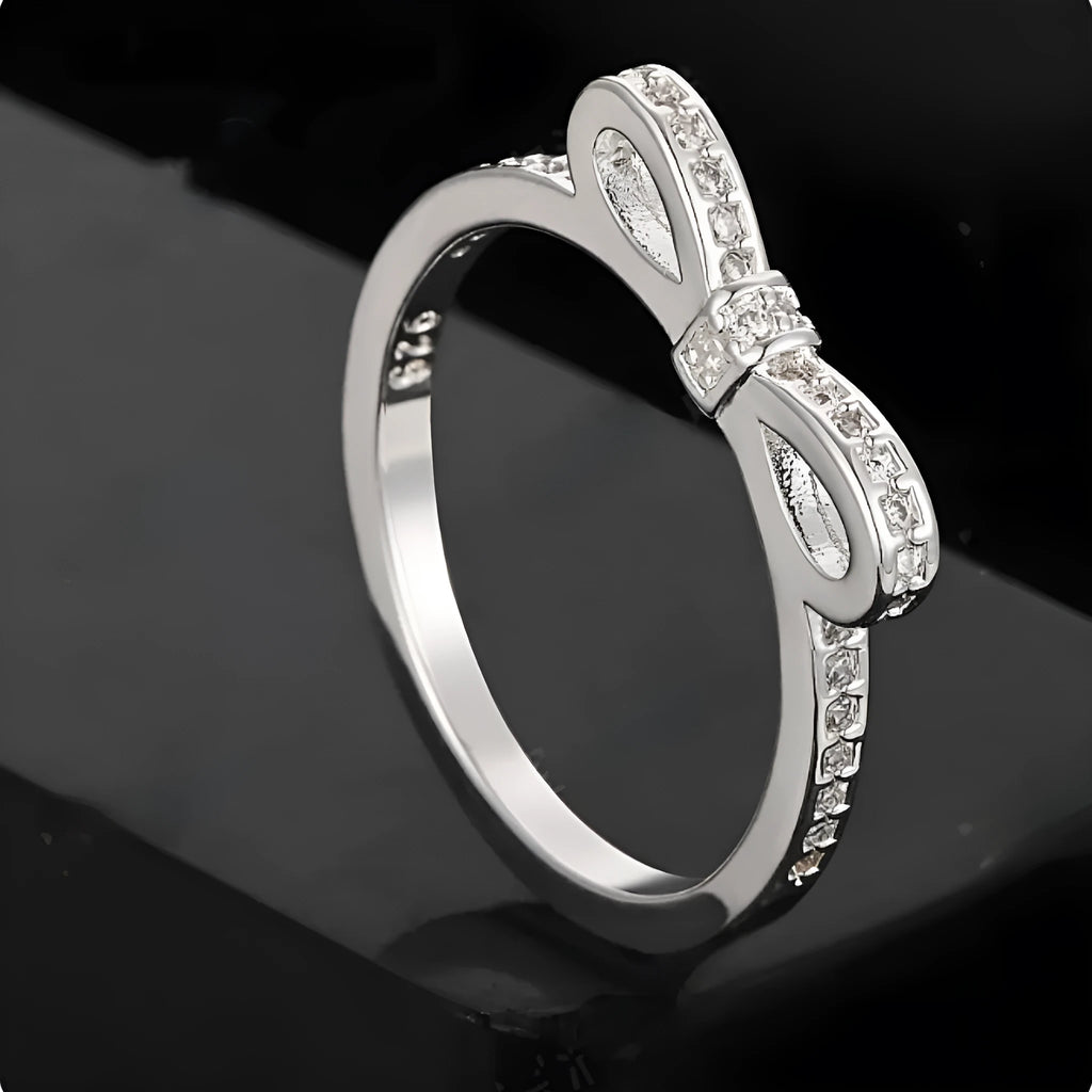 Close-up of a silver-tone bow-shaped ring with sparkling zircon crystal accents on a hand.