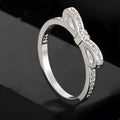 Close-up of a silver-tone bow-shaped ring with sparkling zircon crystal accents on a hand.