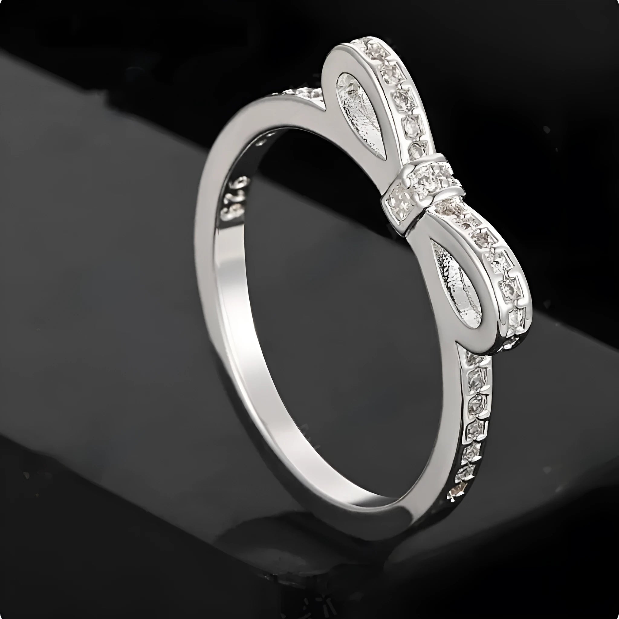 Close-up of a silver-tone bow-shaped ring with sparkling zircon crystal accents on a hand.