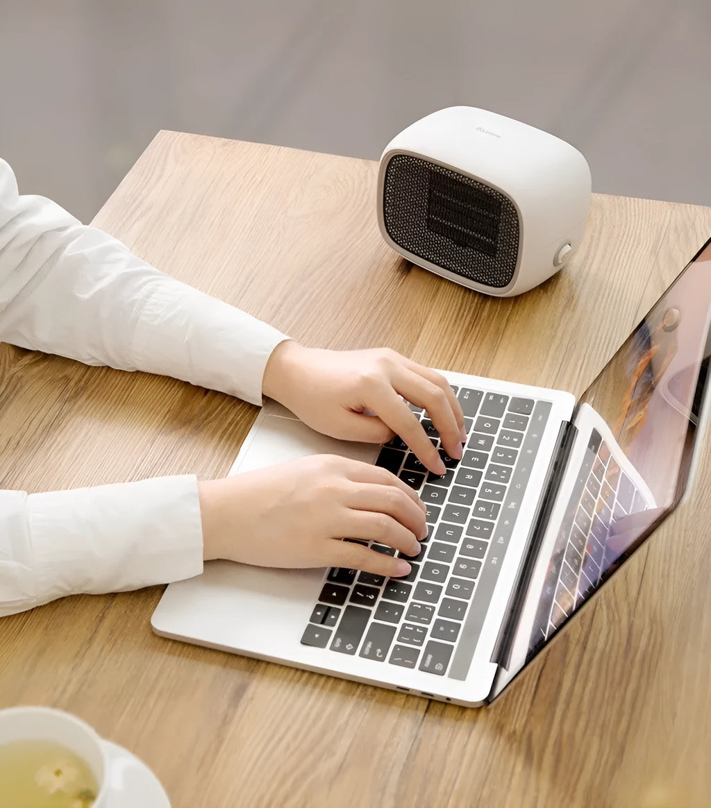Small green portable ceramic fan heater on a desk showing its compact size.
