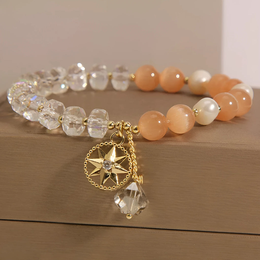 Gold-plated women's bracelet with an eight Awn star charm holding an inlaid orange opal crystal.