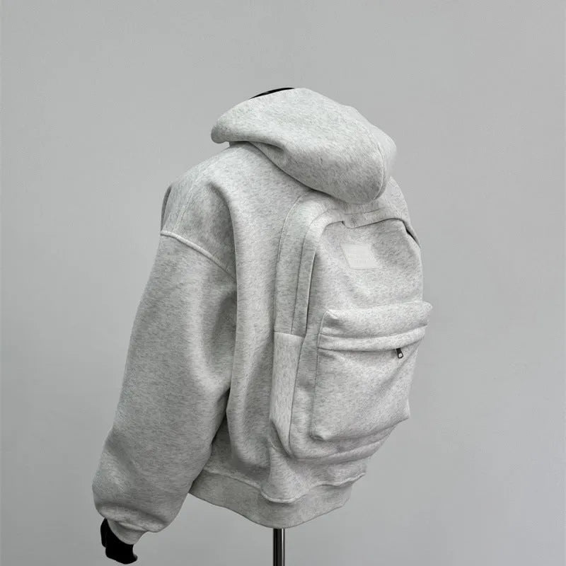 Man wearing a light gray hooded coat with a schoolbag design detail on the back.