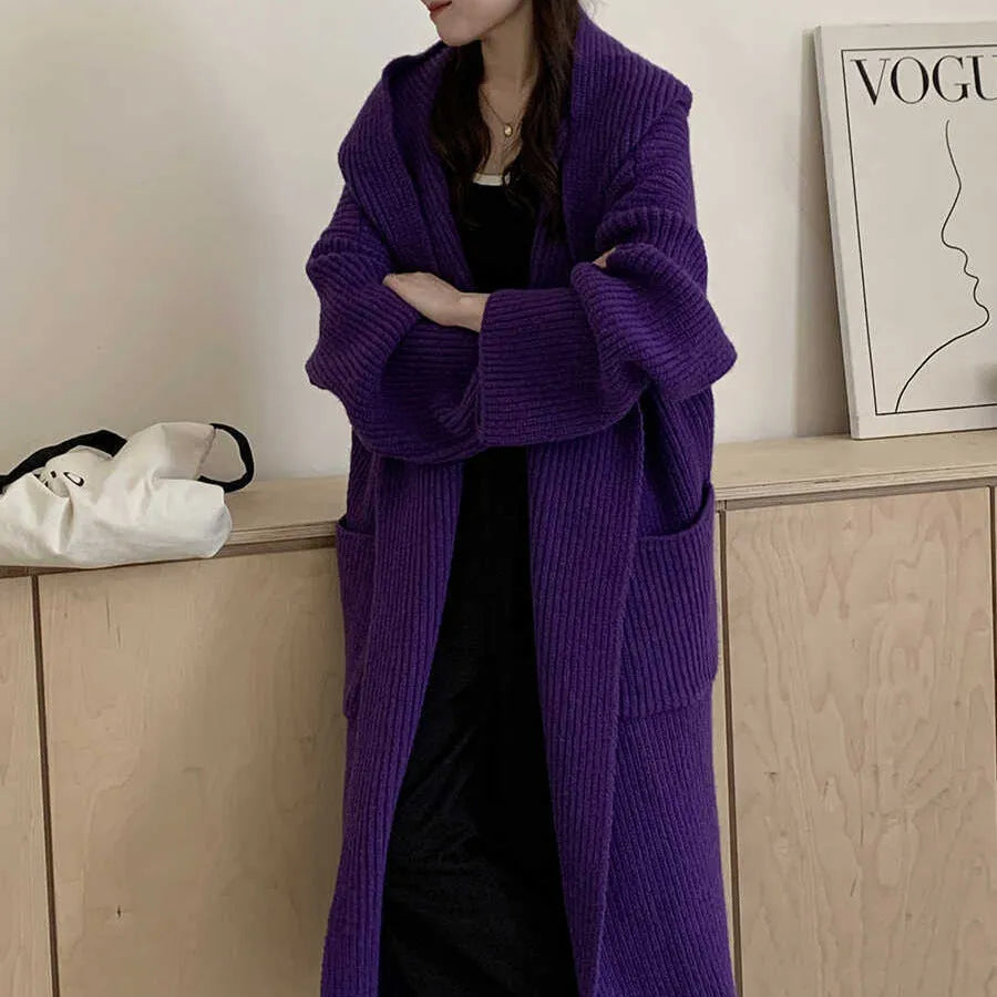 Woman wearing a long loose hooded cardigan coat in acrylic fabric, open as a cardigan.