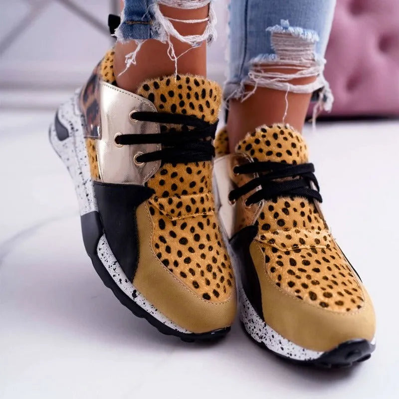 Women's suede sneakers with a wedge heel in leopard print, shown on a foot.