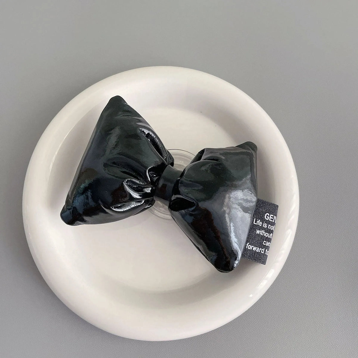 Girl's leather bow lazy bracket with transparent support in black, shown on a plain background