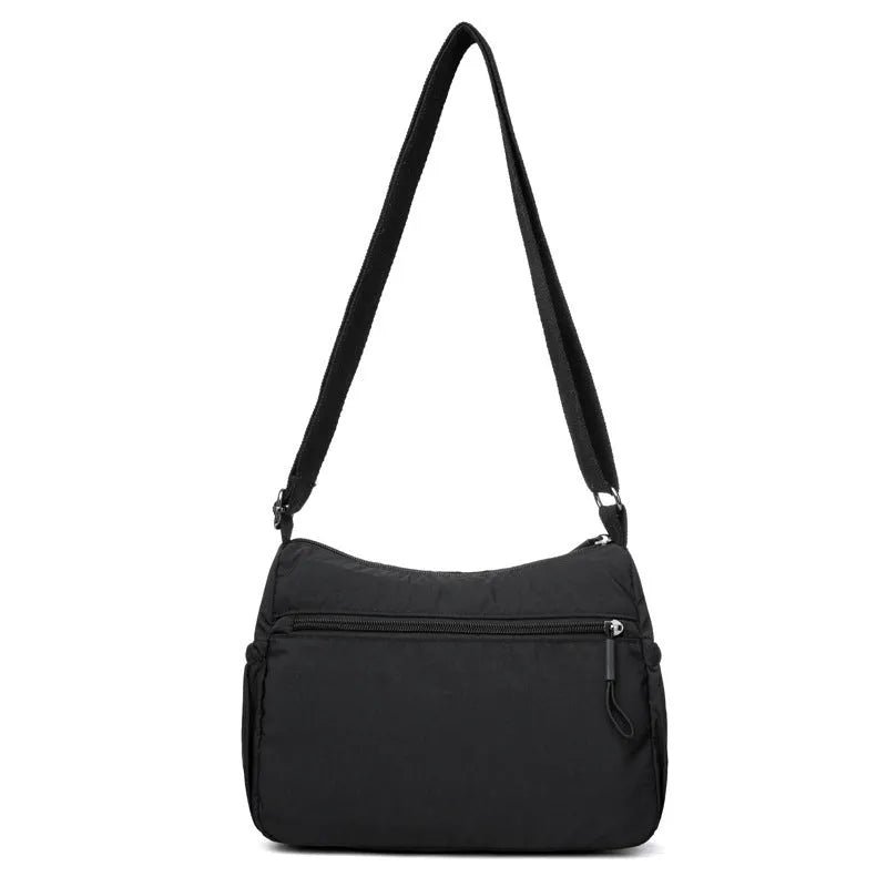 Soft water-repellent nylon crossbody bag in black with an outer pocket and zipped main compartment.