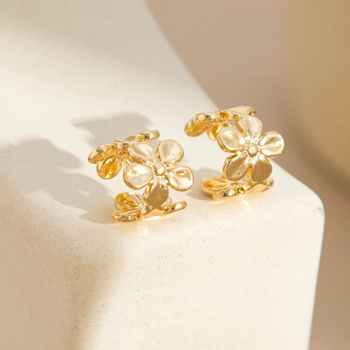 Gold-coloured drop earrings with a detailed starfish and conch shell design on a white background.