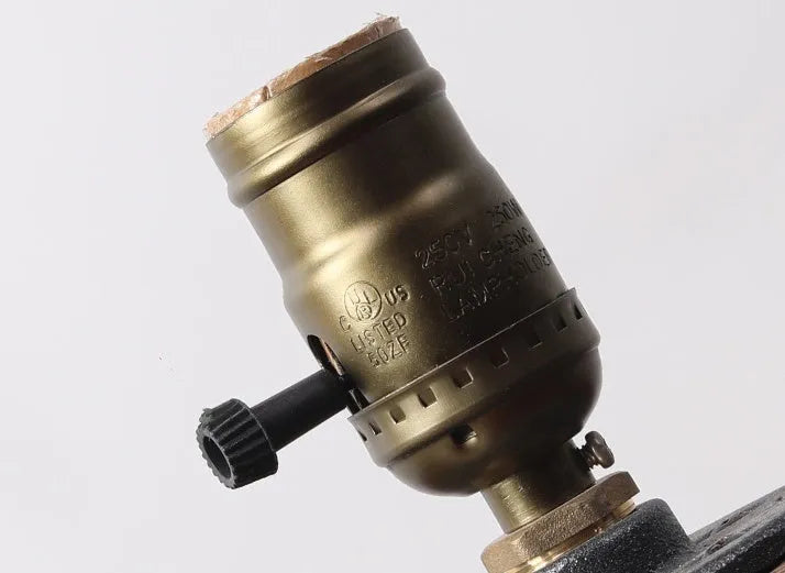 Small wooden and iron water pipe style table lamp on a surface.
