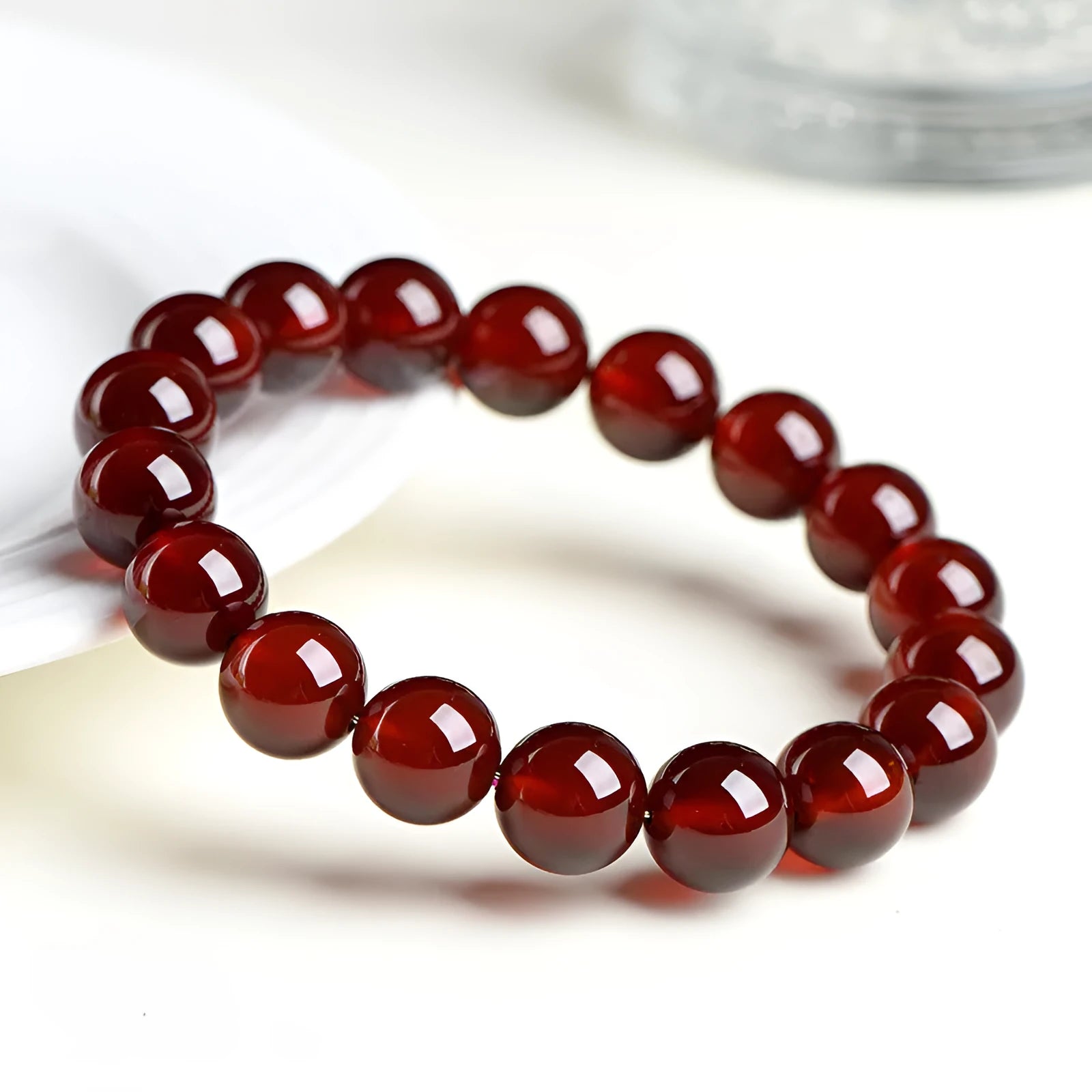 Natural Orange Red Garnet ball bead bracelet with a metal Ruyi charm on a white background.