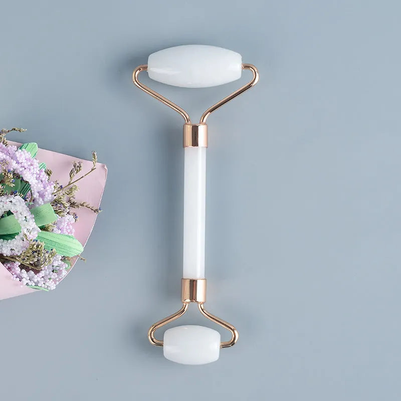 White jade double-headed facial roller and gua sha board set on a plain background.