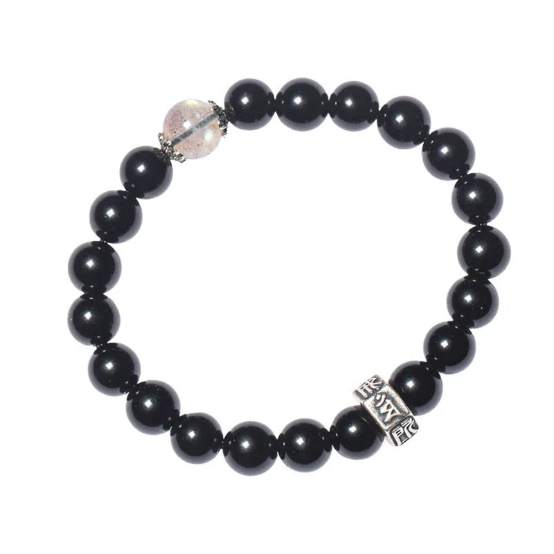 Obsidian bead bracelet with a hand-carved zodiac animal and bodhisattva charm on a wrist.