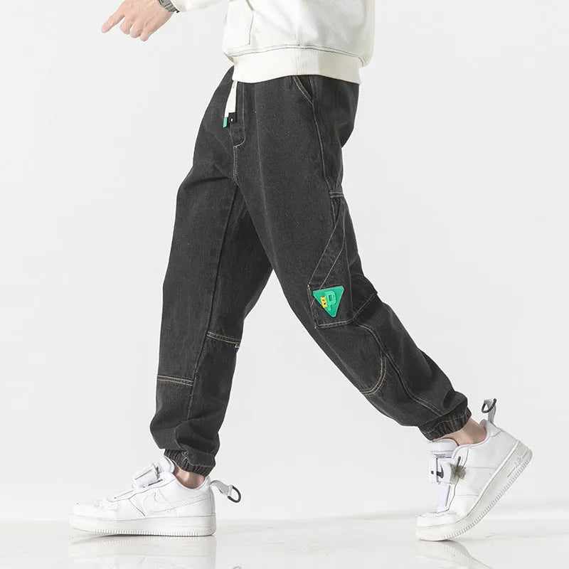 Men's loose-fit tapered cotton trousers in grey, shown laid flat, highlighting the tapered leg silhouette.