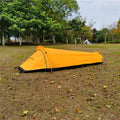 Single person sleeping bag tent in army green set up outdoors, showing rain fly and aluminium rod poles.