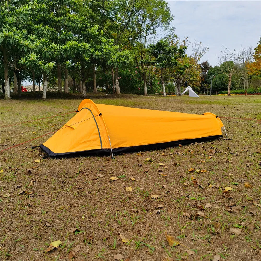Single person sleeping bag tent in army green set up outdoors, showing rain fly and aluminium rod poles.