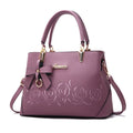 Ladies fashion handbag in artificial leather with crossbody strap, available in multiple colours including black and pink