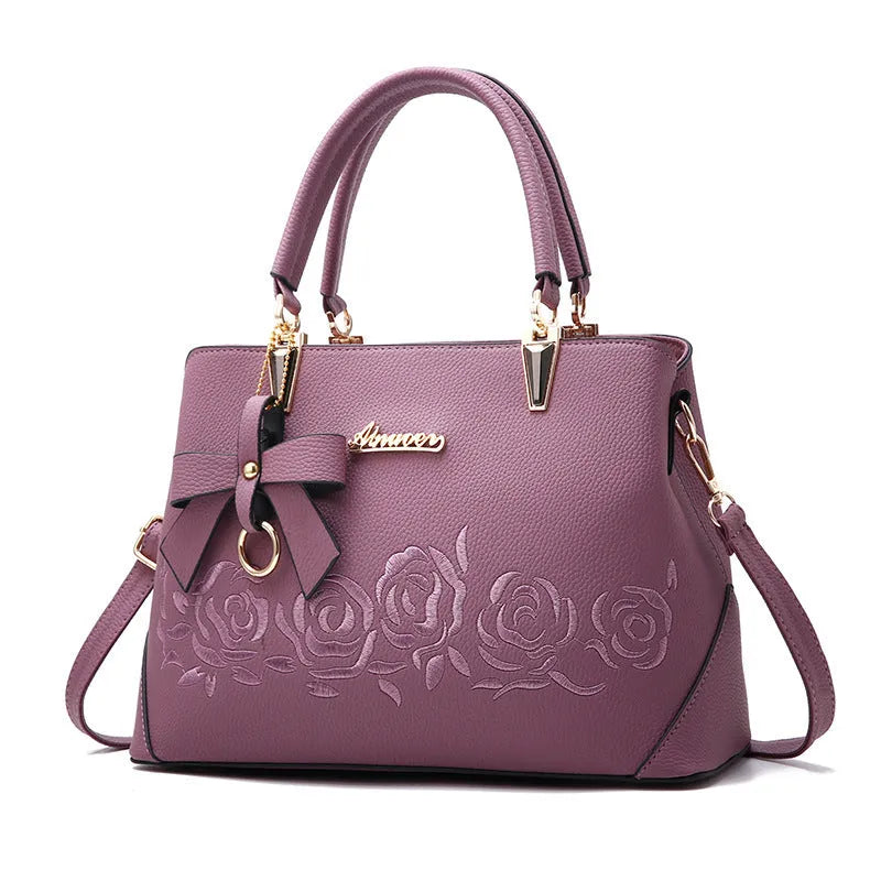 Ladies fashion handbag in artificial leather with crossbody strap, available in multiple colours including black and pink