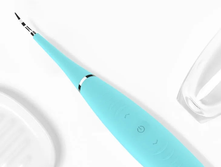 Pink and blue waterproof electric dental scaler with silicone handle and charging cable on a bathroom counter.