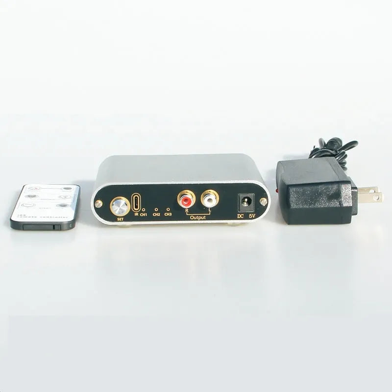 Silver aluminium audio source selector switch unit with front panel button and infrared remote.